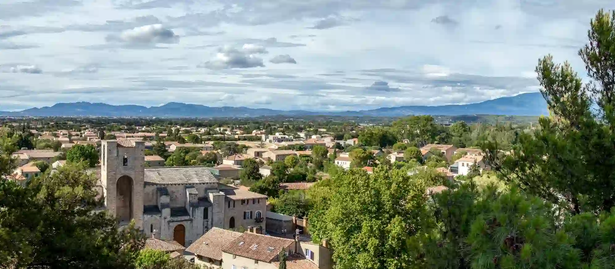 Vue panoramique sur le village de Pernes-les-Fontaines, avec en arrière-plan les montagnes et la nature environnante.