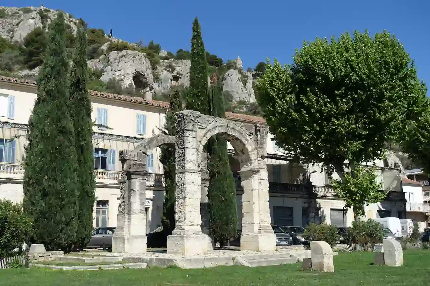 Vestige de l'Arc Romain de Cavaillon avec en arrière-plan des bâtiments provençaux et la colline Saint-Jacques.