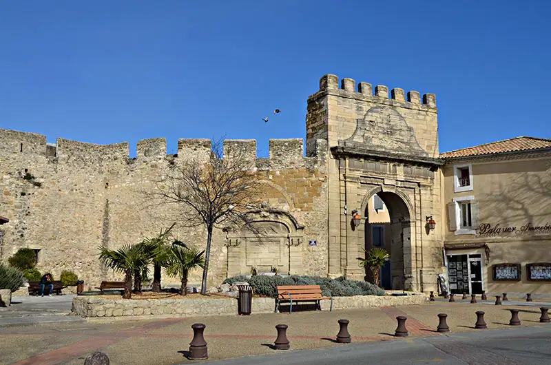 Vue de la porte historique de Morières-les-Avignon, avec ses bâtiments typiques et son cadre pittoresque.