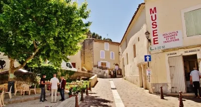 Rue pittoresque de Châteaurenard avec un musée local et des visiteurs profitant de l’ambiance ensoleillée, entourée de bâtiments provençaux.