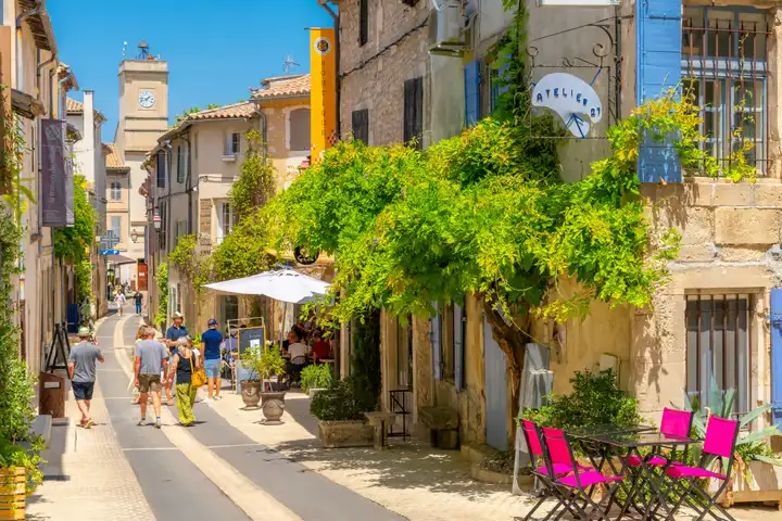 Rue de Saint-Rémy-de-Provence avec des cafés en terrasse et l’horloge de la ville, offrant une ambiance conviviale et pittoresque.